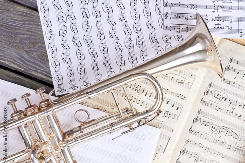 Trumpet on musical notes close up. Musical background with old trumpet and musical notes pages. Classical wind instrument.