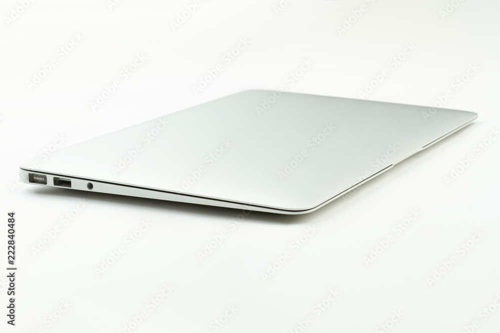 Closed laptop on white desktop. Silver notebook on light surface. Wireless portable technology. Closed laptop on white desktop. Silver notebook on light surface. Wireless portable technology.