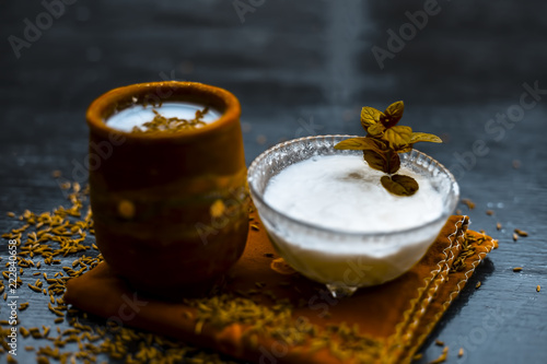 Traditional summer drink i.e. is most popular in Asia and India i.e. Chas or chaas or buttermilk or chhaachh in a clay glass with curd and coriander powder and salt on wooden surface,Close up. photo