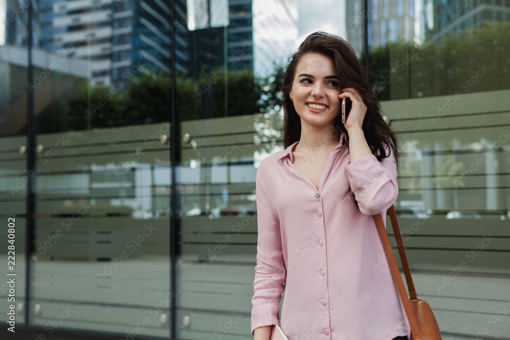 Busy female manager calling with cell telephone outside, woman talking via mobile phone and walking on the city street, student girl having a phone call after university classes.Remore work concept Busy female manager calling with cell telephone outside, woman talking via mobile phone and walking on the city street, student girl having a phone call after university classes.Remore work concept