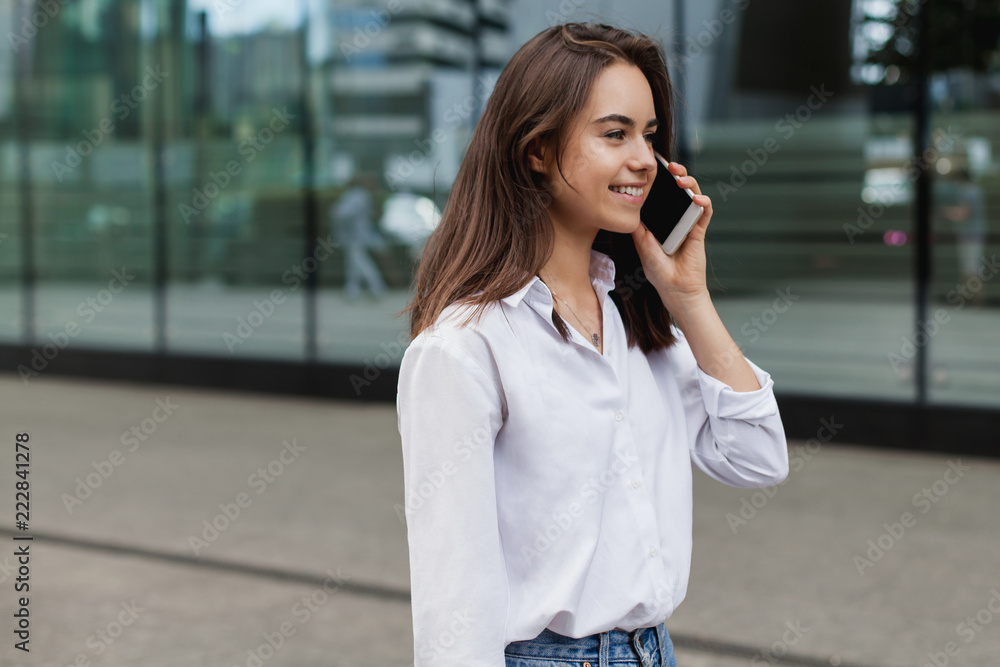 Busy female manager calling with cell telephone outside, woman talking via mobile phone and walking on the city street, manager working remotely and making phone call via modern smartphone outdoors Busy female manager calling with cell telephone outside, woman talking via mobile phone and walking on the city street, manager working remotely and making phone call via modern smartphone outdoors