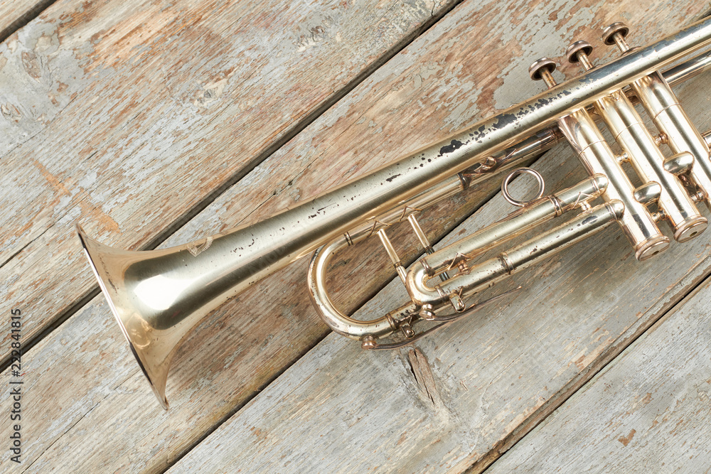 Fototapeta premium Aged trumpet on wooden planks. Old trumpet on vintage wooden background. Instrument of classical music.