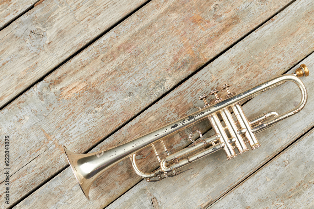 Fototapeta premium Old trumpet and copy space. Rusty trumpet on old wooden boards. Classical music pipe instrument.