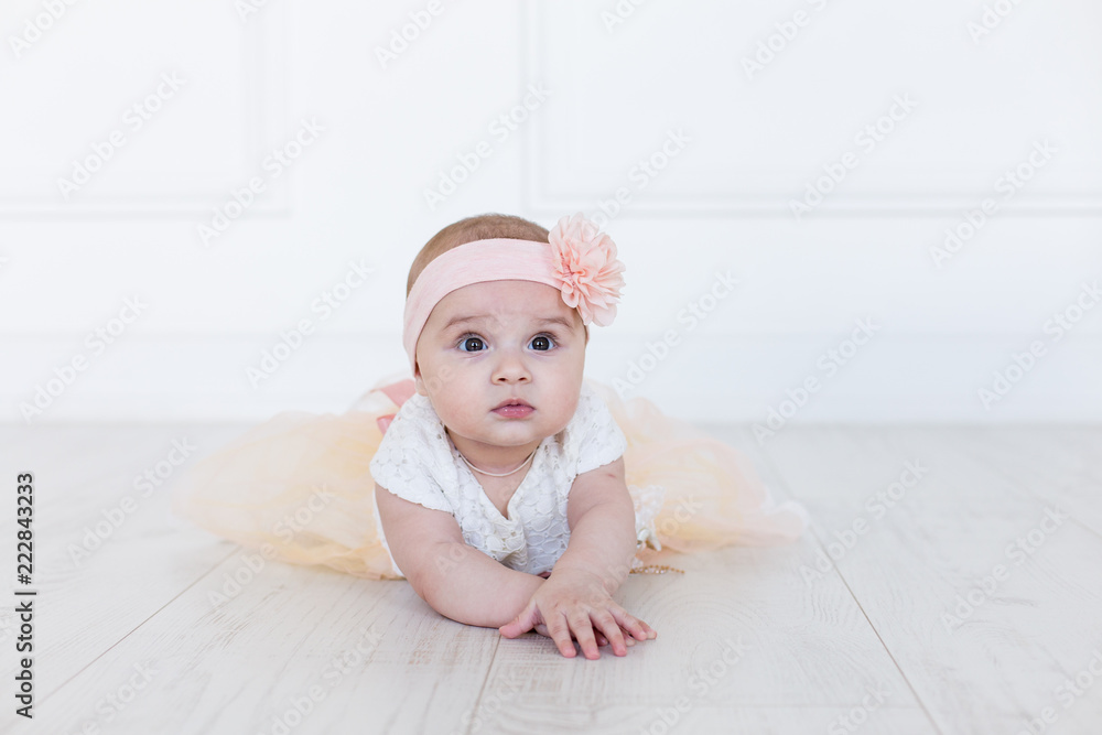 A baby girl is crawling along the floor with an inquisitive and wondering look on her face. Horizontal shot. Cute 6 months girl A baby girl is crawling along the floor with an inquisitive and wondering look on her face. Horizontal shot. Cute 6 months girl