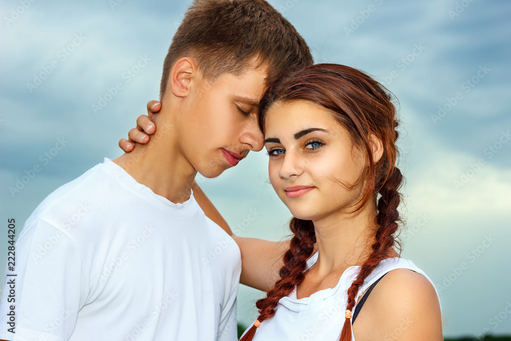 the girl with the guy standing in hugging each other on the sky background