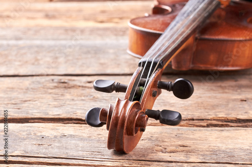 Close up violin on old wooden surface. Detail of musical instrument viola. Cello close up of scroll and peg box. Orchestral musical instrument.