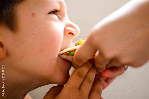 children, diet, culinary and food concept. Boy Child Kid Tortilla with meat and vegetables Starving Eating Concept