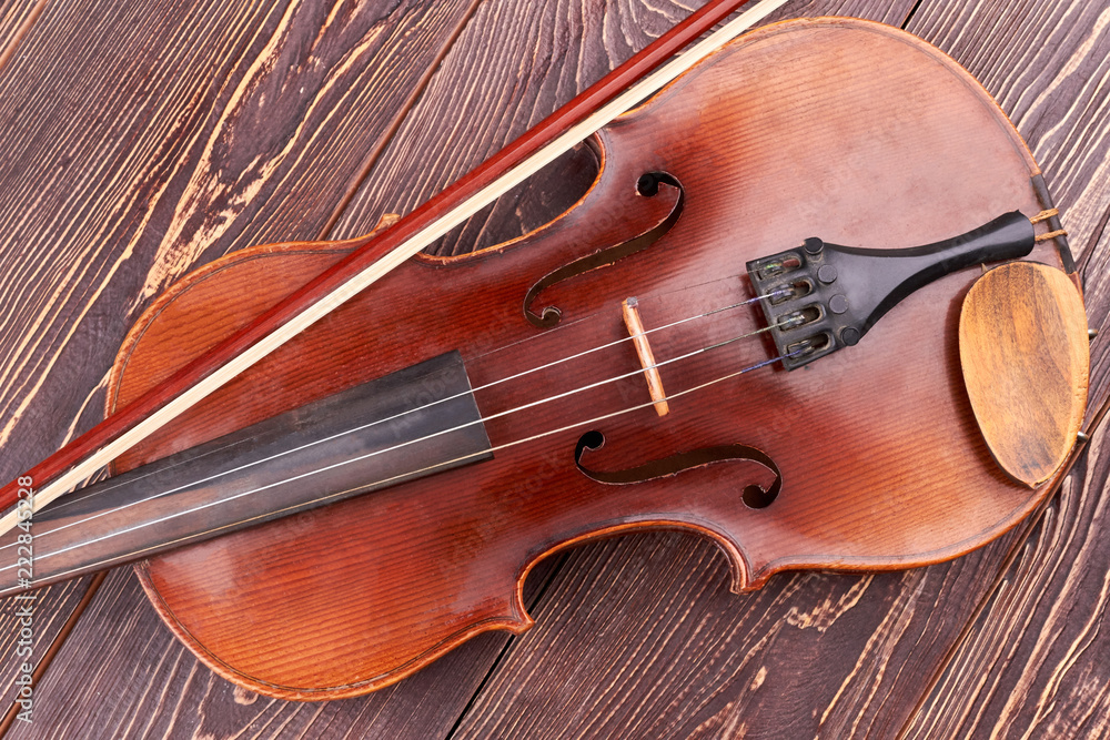Obraz premium Brown violin on wooden table. Vintage violin and fiddle stick. Symbol of classical music.
