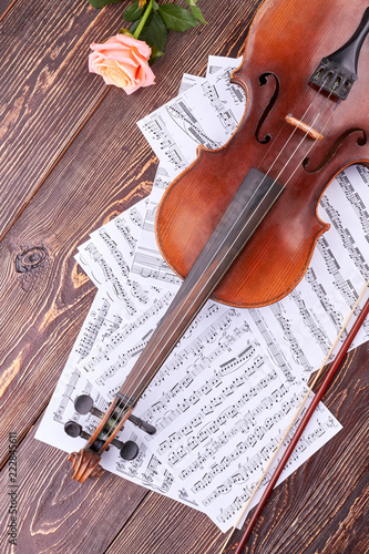 Musical composition on wooden backgoround. Violin, musical notes and rose on brown wooden table, top view. photo