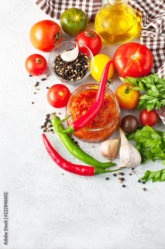 Traditional tomato sauce in glass jar with fresh herbs, tomatoes and olive oil