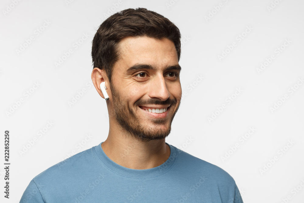 Close up headshot of young smiling man wearing blue t-shirt, listeting to his favorite music track Close up headshot of young smiling man wearing blue t-shirt, listeting to his favorite music track