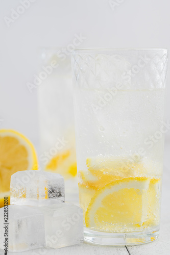 Lemon juice detox water. Mineral water infused with lemons. Wooden white table.