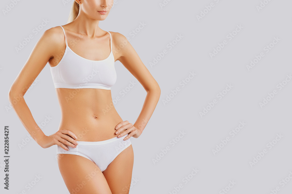 Slim body of a young woman in lingerie on a gray background. - obrazy, fototapety, plakaty 