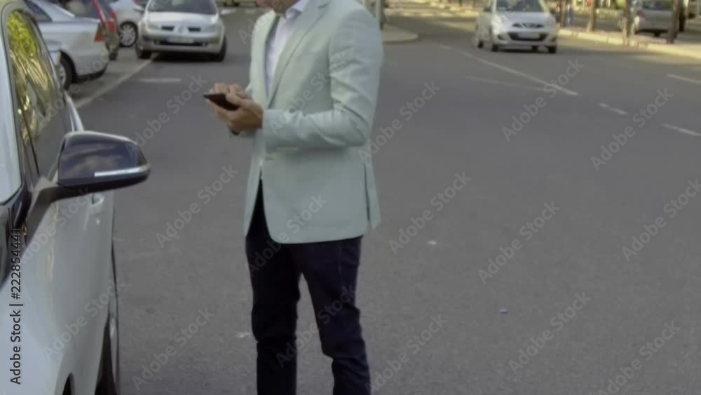 Man with phone sitting into car on road. Businessman in formal wear sitting into modern car. Stylish driver. Man opening car door with smartphone. Transportation concept Man with phone sitting into car on road. Businessman in formal wear sitting into modern car. Stylish driver. Man opening car door with smartphone. Transportation concept