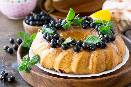 Delicious dessert black currant, sweet delicious holiday cake with black currant and lemon glaze on a table in a rustic style. Copy space.