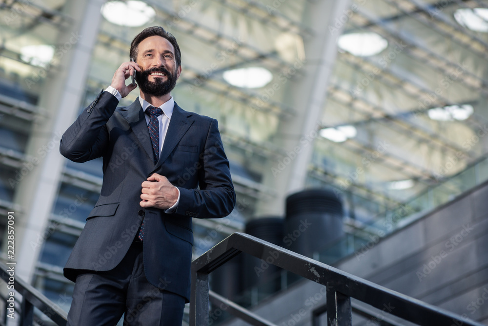 Low angle of a cheerful businessman talking on phone Low angle of a cheerful businessman talking on phone