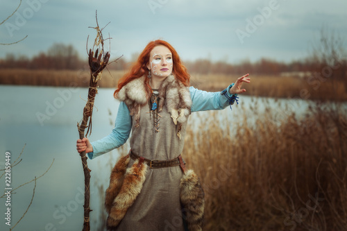 Pagan woman is a shaman with a staff in her hands. photo