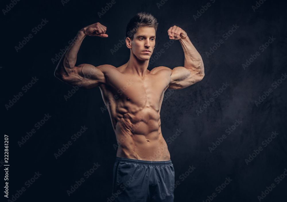 Fototapeta premium Handsome shirtless man with stylish hair and muscular ectomorph shows his biceps.