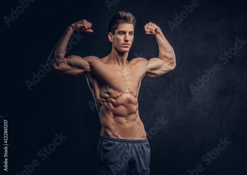 Handsome shirtless man with stylish hair and muscular ectomorph shows his biceps.