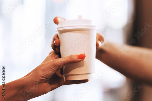 Barista passes coffee to a visitor in a popular coffee shop, hands and a glass of coffee are shot close-up.