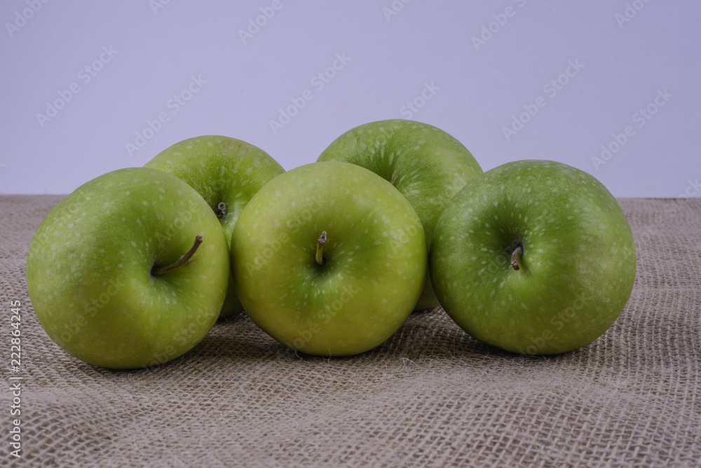 Five green granny smith apples on burlap surface on white background. Five green granny smith apples on burlap surface on white background.