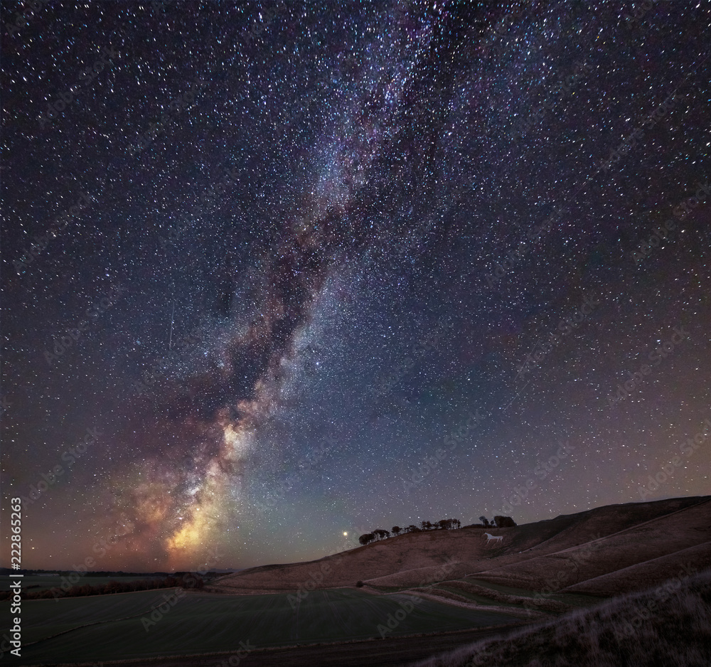 Vibrant Milky Way composite image over landscape of ancient chalk white horse at Cherhill in Wiltshire
