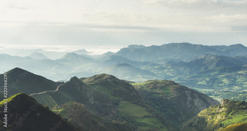 morning mist in the mountain peaks on natural landscape. Green valley on background foggy dramatic sky. Panorama horizon perspective view of scenery hills Northern Spain mountain. Travel concept