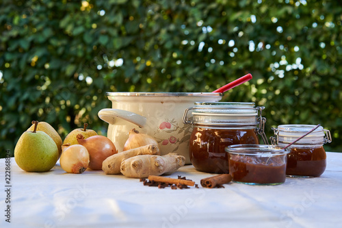 Cooking and preserving of homemade spicy pear chutney in the garden typical british food consist from pears, onion, garlic, ginger and spice, kilner jars and cooking pot photo