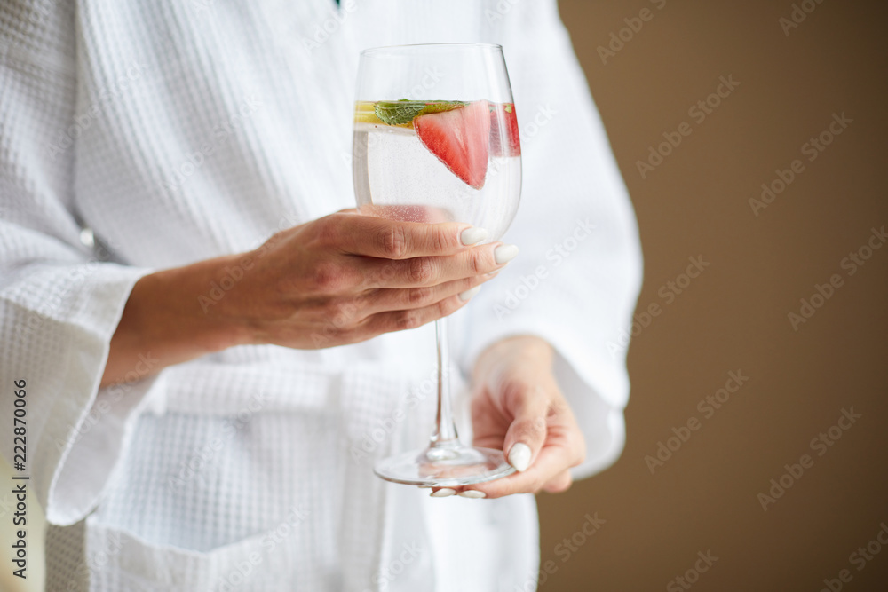 Young relaxed woman holding fresh strawberry cocktail while relaxing in day spa center Young relaxed woman holding fresh strawberry cocktail while relaxing in day spa center