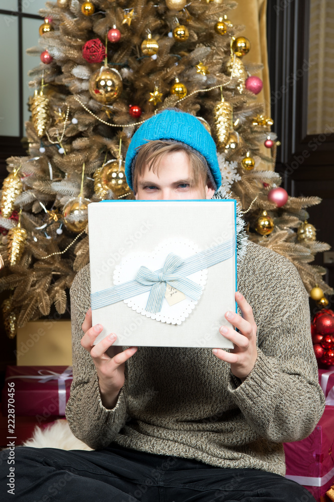 Man cover face with gift box at Christmas tree