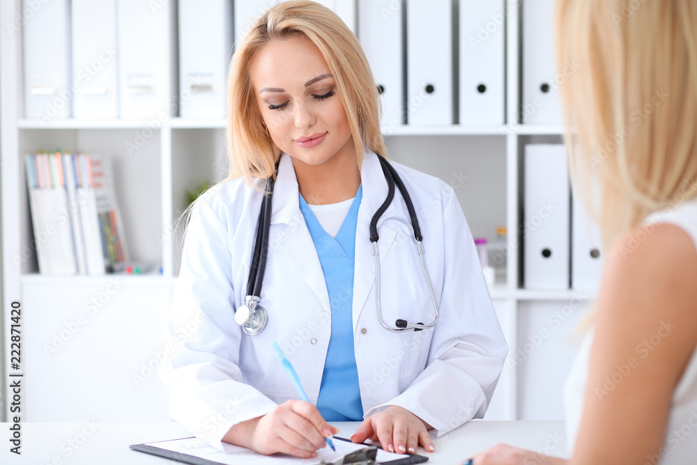 Doctor and patient discussing something while sitting at the table at hospital. Medicine and health care concept Doctor and patient discussing something while sitting at the table at hospital. Medicine and health care concept