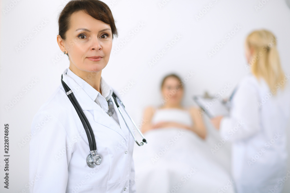 Female doctor smiling on the background with patient and his doctor Female doctor smiling on the background with patient and his doctor