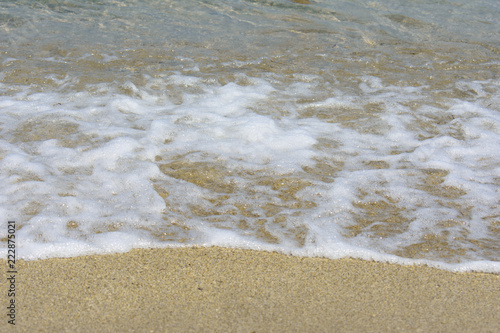 The foamed sea water on the sandy beach