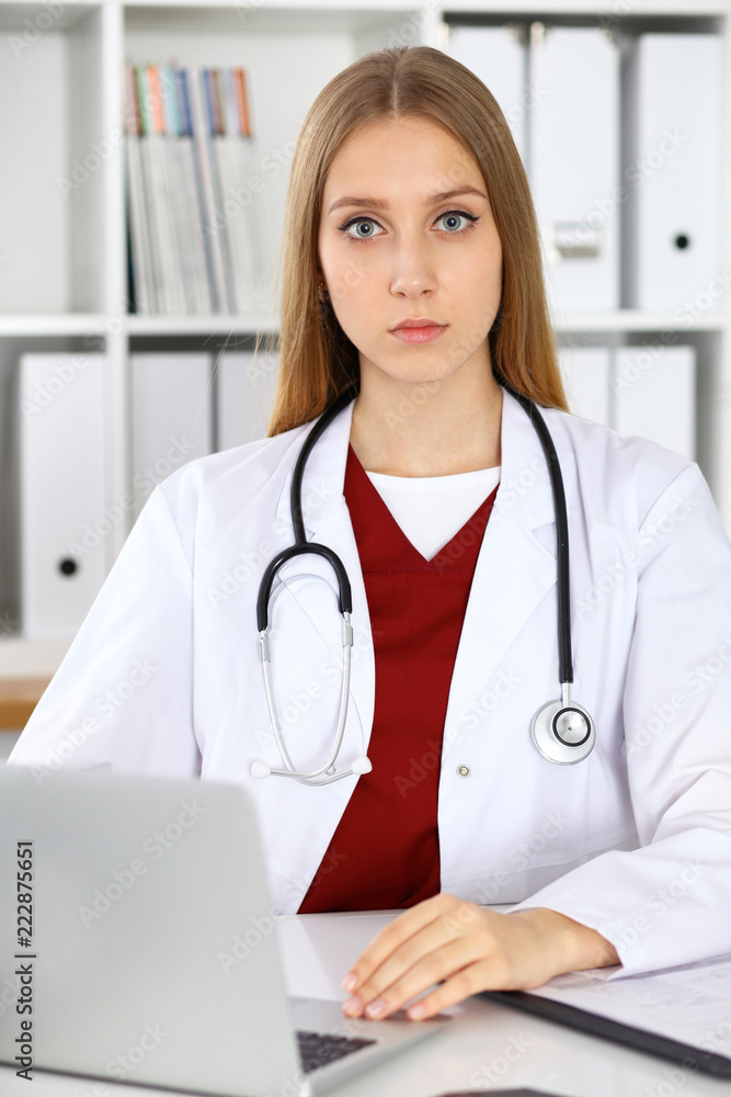 Brunette female doctor using laptop computer in hospital. Healthcare, insurance and medicine concept Brunette female doctor using laptop computer in hospital. Healthcare, insurance and medicine concept