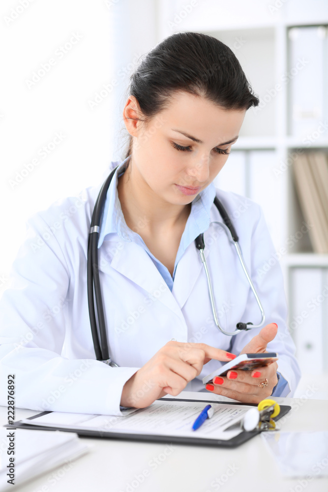 Young brunette female doctor at working place in hospital. Health care, insurance and help concept Young brunette female doctor at working place in hospital. Health care, insurance and help concept