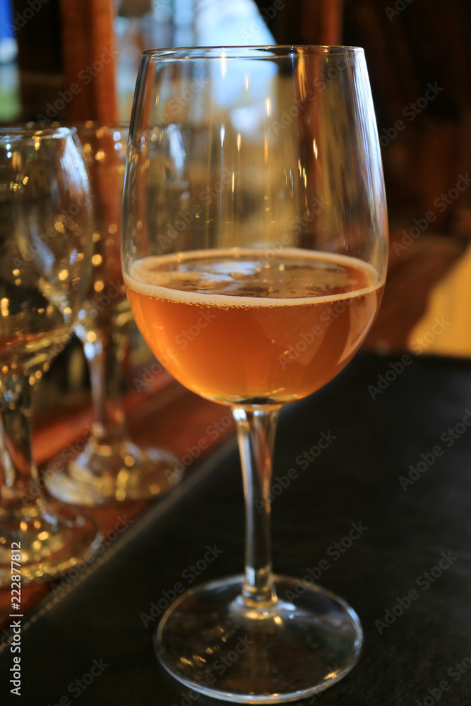 Vertical photo of a glass of amber color chilled craft beer on the dining table Vertical photo of a glass of amber color chilled craft beer on the dining table