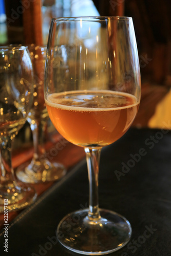 Vertical photo of a glass of amber color chilled craft beer on the dining table 
