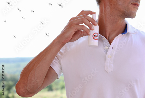 Mosquito repellent. Man using insect repellent spray from bottle outdoors.