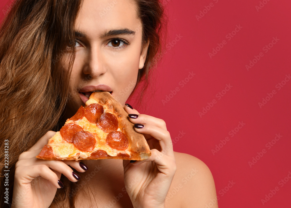 Young beautiful woman eating slice of pepperoni pizza on pink red Young beautiful woman eating slice of pepperoni pizza on pink red