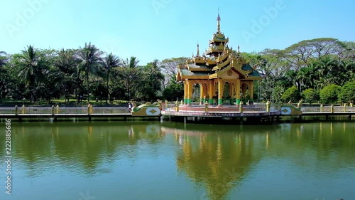 The scenic Buddhist shrine with carved pyatthat roof is reflected in pond of Theingottara park, Yangon, Myanmar. photo