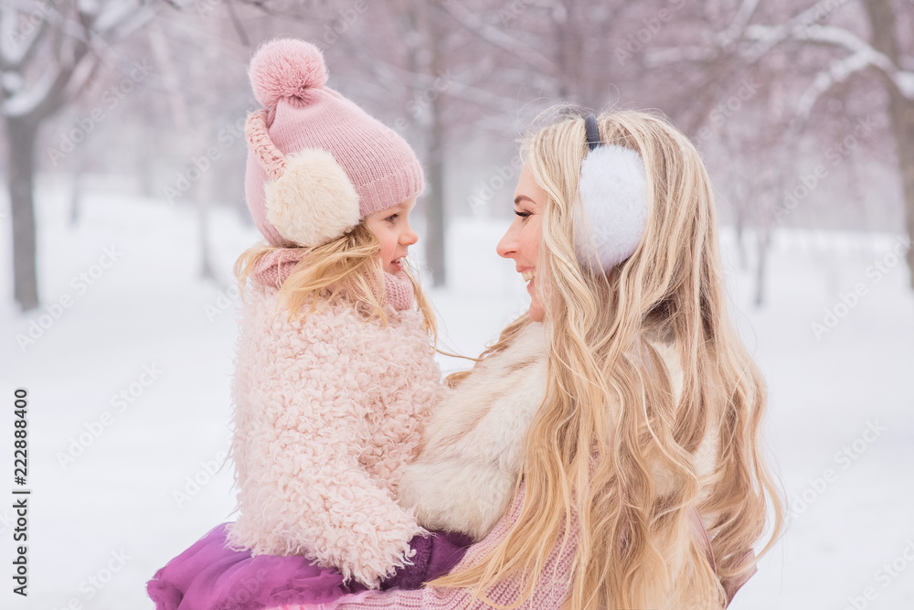 mother with long blond curls hugs her beautiful little daughter in a pink hat with a bubo mother with long blond curls hugs her beautiful little daughter in a pink hat with a bubo