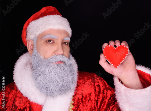 santa claus or holy valentine holds a red heart on a dark background
