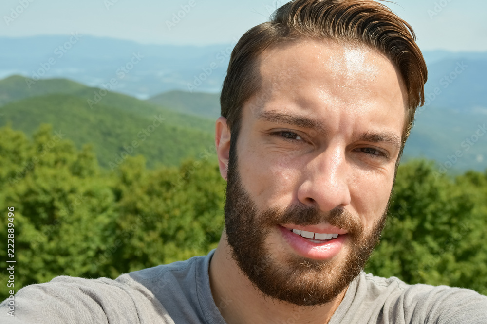 Fototapeta premium Man stands exhausted after a hike to the end of a trail
