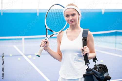 Waist up portrait of beautiful blonde woman posing in tennis court before practice and looking at camera , copy space