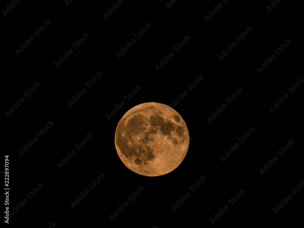 Beautiful close up photograph of a full micro moon with a yellow hue in a dark black night sky. Beautiful close up photograph of a full micro moon with a yellow hue in a dark black night sky.
