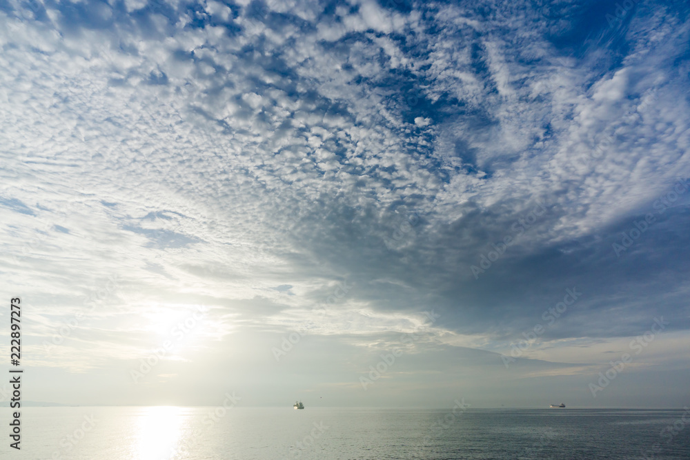 朝の海の光る波と青空を覆う白い雲