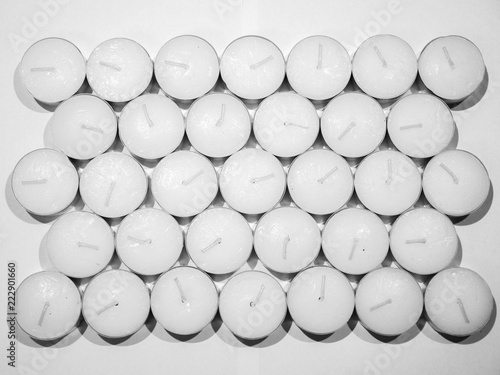 Canvas Print Closeup unsaturated photograph of lots of unlit white tea candles in silver colored metal enclosure organized in rows laid out on a counter making a beautiful background image, wallpaper or backdrop