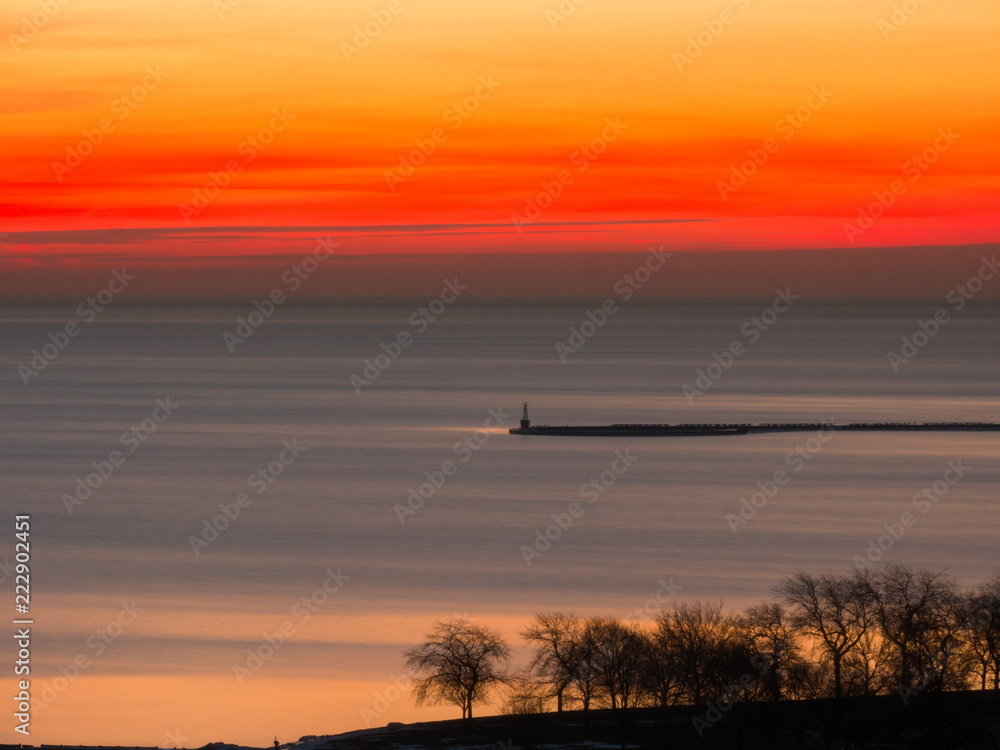 Beautiful landscape photograph of a vivid red orange and yellow sunrise in Chicago over the water of Lake Michigan