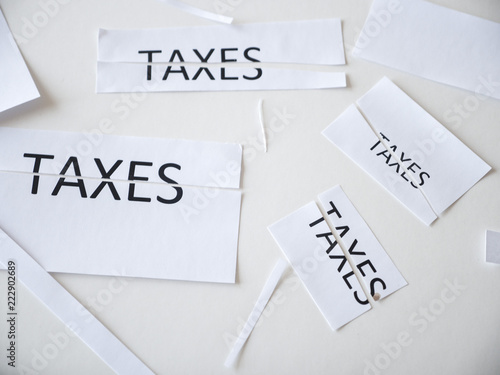 Pieces of paper and scraps of paper with some cut in half with the word taxes written on it representing tax cuts at federal and state governments saving Americans money with increased deductions.