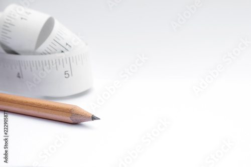 Close-up Pencil and paper measuring tape roll  on white background with copy space